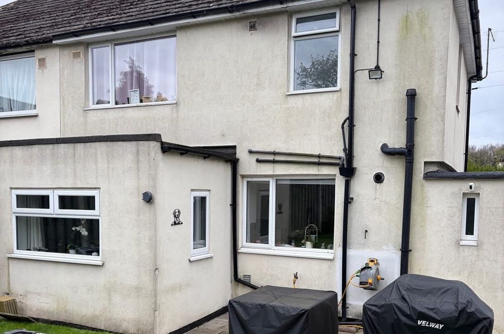 Rear of a rendered semi-detached house before cleaning